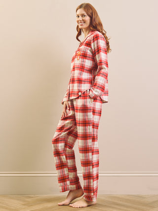 a person wearing a red, white, and black tartan plaid button-up shirt with a small embroidered orange-and-white mushroom patch on the chest pocket.