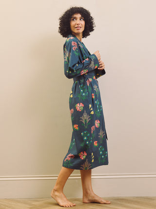 Woman wearing a navy blue floral patterned robe against a beige wall.