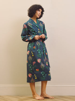 Woman wearing a navy blue floral patterned robe against a beige wall.