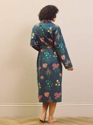 Woman wearing a navy blue floral patterned robe against a beige wall.