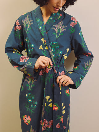Woman wearing a navy blue floral patterned robe against a beige wall.