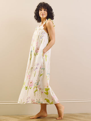 Woman wearing a floral night dress standing against a plain wall.