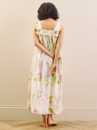 Woman wearing a floral night dress standing against a plain wall.