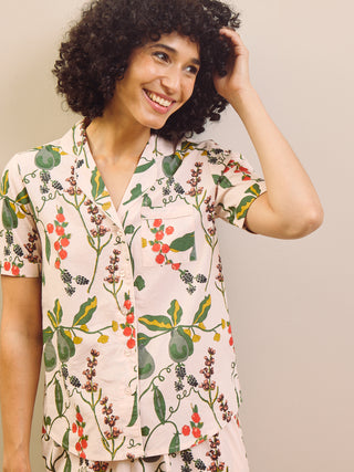 Woman wearing a pear & floral patterned pyjama shirt against a neutral background