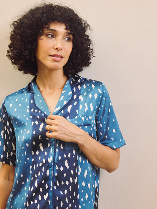 Woman wearing a blue patterned pyjama shirt against a plain background