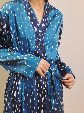 Woman wearing a blue short fawn print robe dressing gown against a beige wall.