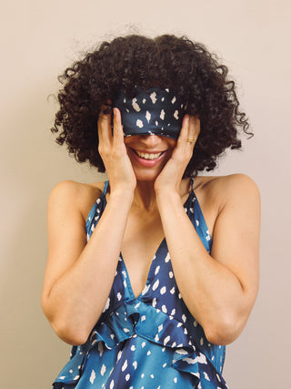 Woman wearing a blue fawn print night dress and matching sleep mask against a beige background