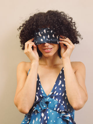 Woman wearing a matching sleep mask and night dress with a beige background