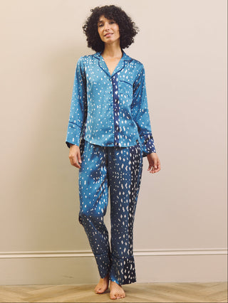 Woman wearing blue and white fawn patterned pyjamas against a beige wall.