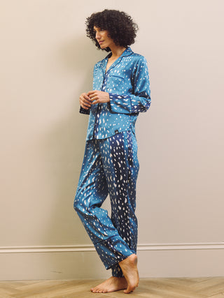 Woman wearing blue and white fawn patterned pyjamas against a beige wall.