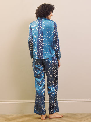 Woman wearing blue and white fawn patterned pyjamas against a beige wall.