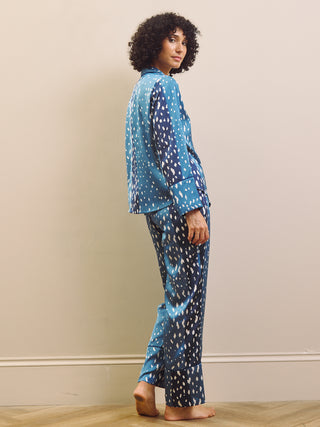 Woman wearing blue and white fawn patterned pyjamas against a beige wall.