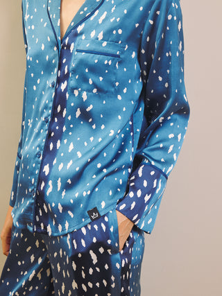Woman wearing blue and white fawn patterned pyjamas against a beige wall.