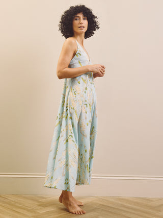 Woman wearing a floral night dress standing against a plain background