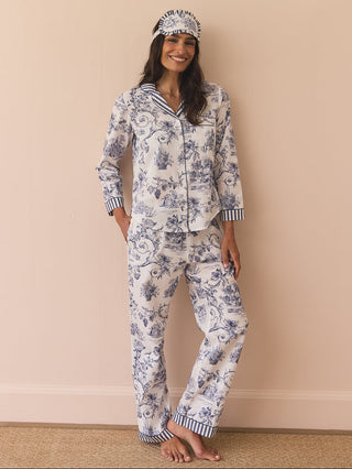 Woman wearing a floral pyjama set and eye mask against a beige wall.