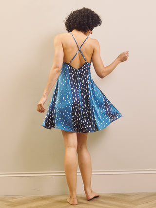 Woman wearing a blue nightdress with white fawn print patterns against a beige background