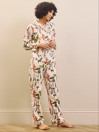 Woman wearing a pear & floral pyjama set against a plain wall.