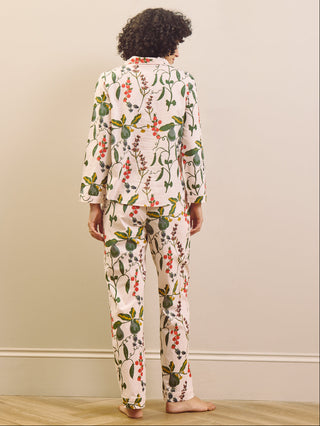 Woman wearing a pear & floral pyjama set against a plain wall.