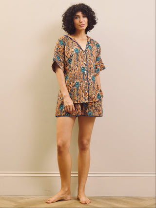 Woman wearing a feather patterned short pyjama set standing against a plain wall.
