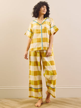 model wears yellow large Ingham check pyjama set against a beige wall