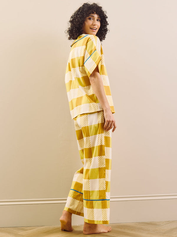 model wears yellow large Ingham check pyjama set against a beige wall, back detail