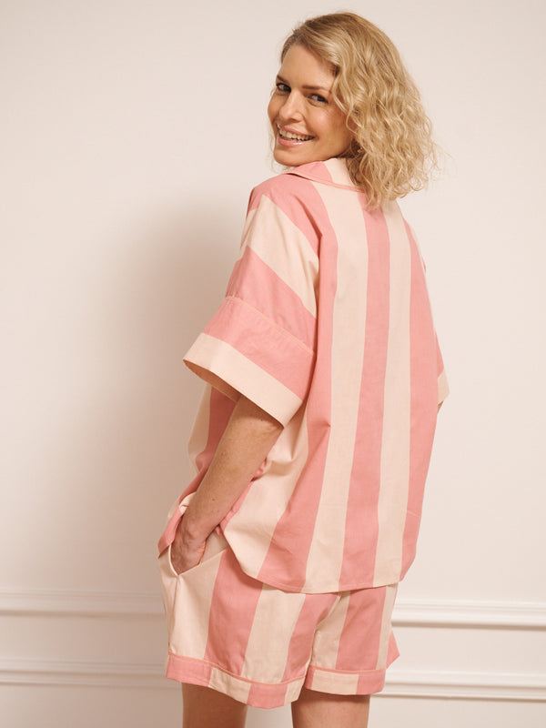 Model wearing a pink and white striped pyjama set against a white background. back detail. 