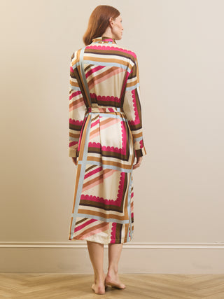A woman stands with her back to the camera wearing a long-sleeved wrap dressing gown robe with a retro geometric pattern in beige, brown, pink, and light blue.