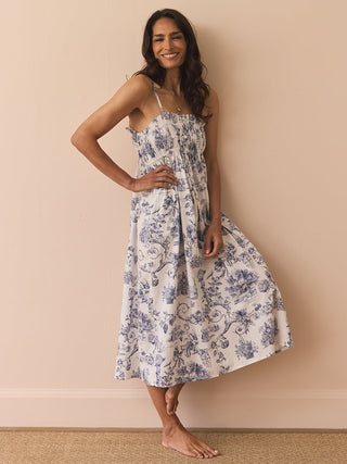 Model wears a navy and white toil print night dress against a beige wall. 