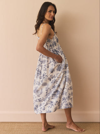 Model wears a navy and white toil print night dress against a beige wall. 
