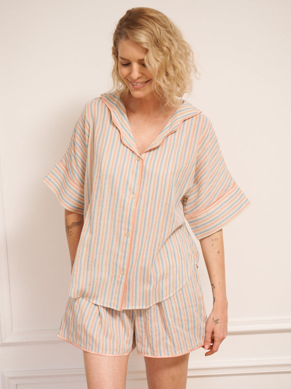 Women’s pastel stripe cotton gauze shortie pyjama set with oversized button-up top, short sleeves, open collar and matching shorts with pockets, shown on model indoors.