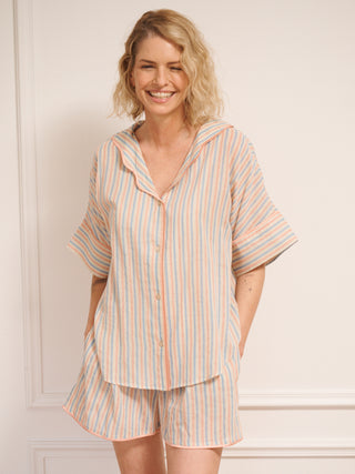 Women’s pastel stripe cotton gauze shortie pyjama set with oversized button-up top, short sleeves, open collar and matching shorts with pockets, shown on model indoors.