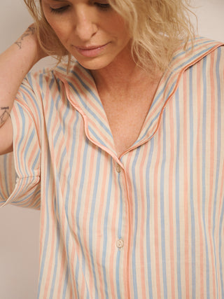 Women’s pastel stripe cotton gauze shortie pyjama set with oversized button-up top, short sleeves, open collar and matching shorts with pockets, shown on model indoors. collar detail. 