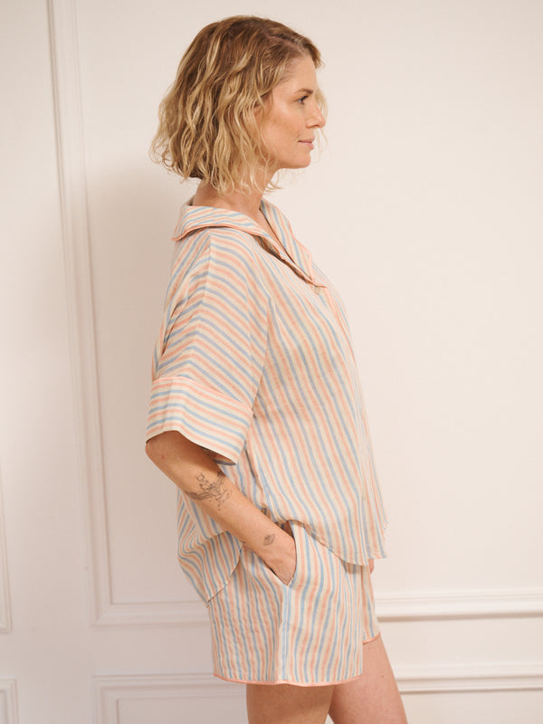 Women’s pastel stripe cotton gauze shortie pyjama set with oversized button-up top, short sleeves, open collar and matching shorts with pockets, shown on model indoors.