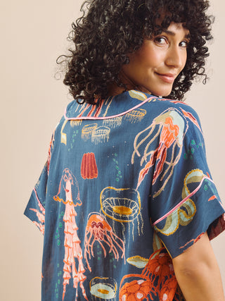 Woman wearing a blue pyjama shirt with colorful jellyfish design on a beige background