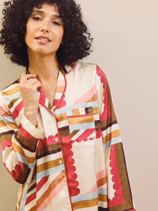 Woman wearing a colourful patterned pyjama top against a beige background