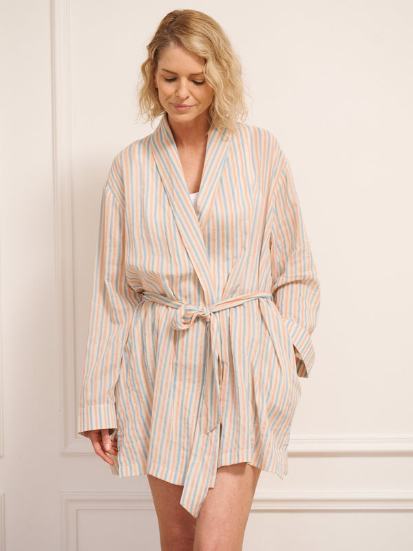 Model wearing a striped dressing gown and shorts set against a white wall.