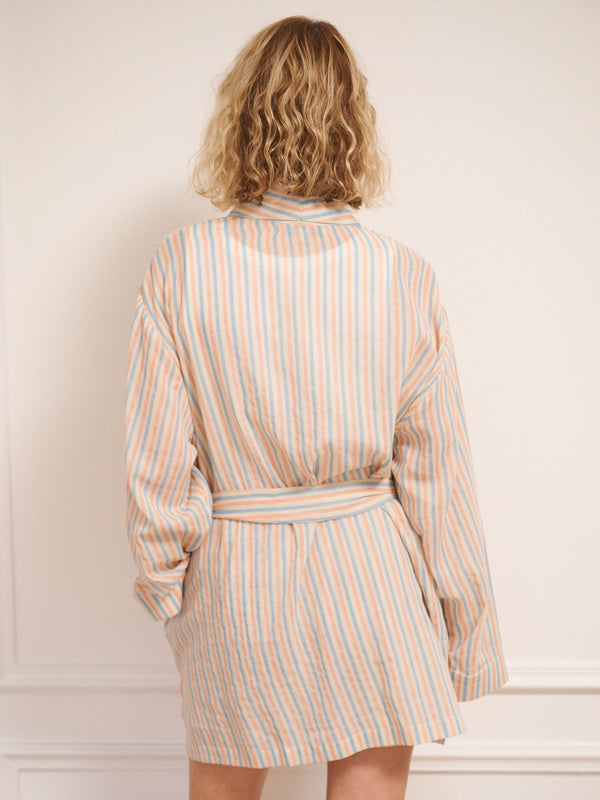 Model wearing a striped dressing gown and shorts set against a white wall. back detail