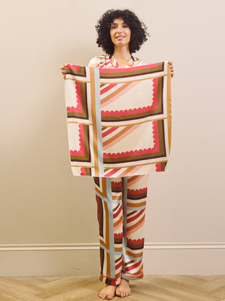 Woman holding a patterned scarf against a plain background