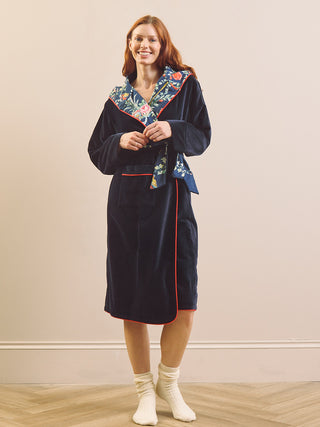 a moved wearing a velvet dressing gown with contrast floral fabric on the inside of the hood and reversible belt tie. 