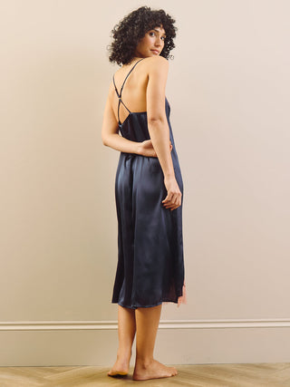 Model wears Navy Satin Night Dress with cross over back against a plain wall