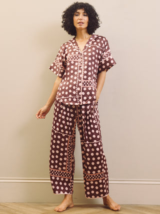 Woman wearing a polka dot pyjama set against a plain background