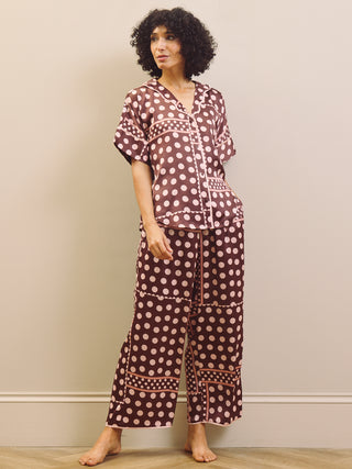 Woman wearing a polka dot pyjama set against a plain background
