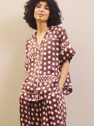 Woman wearing a brown polka dot pyjama set against a beige background
