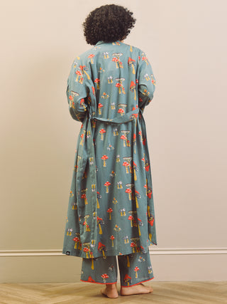 Person wearing a long, patterned  mushroom print dressing gown robe standing against a plain background