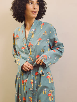 Woman wearing a grey robe with mushroom pattern against a beige background