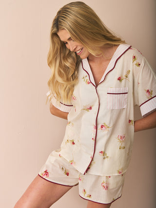 Woman wearing a short floral pyjama set against a plain background
