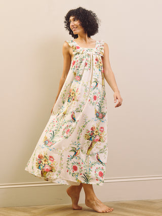 Woman wearing a floral night dress standing against a plain wall.