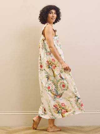 Woman wearing a floral night dress standing against a plain wall.