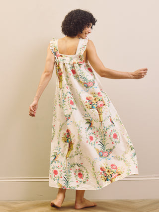 Woman wearing a floral night dress standing against a plain wall.