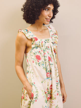 Woman wearing a floral night dress standing against a plain wall. Frill detail. 